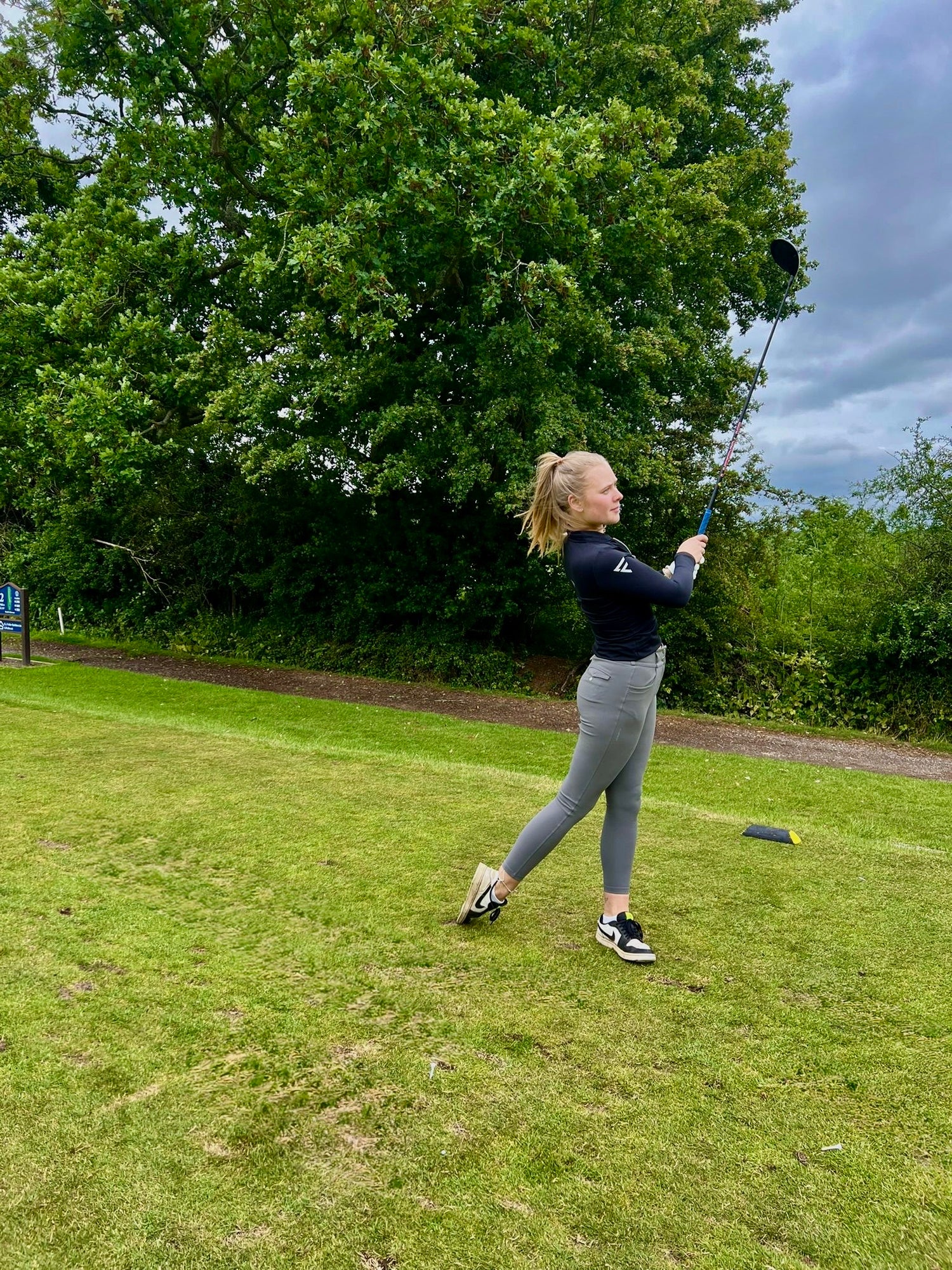 Person playing golf on a grassy course with trees in the background