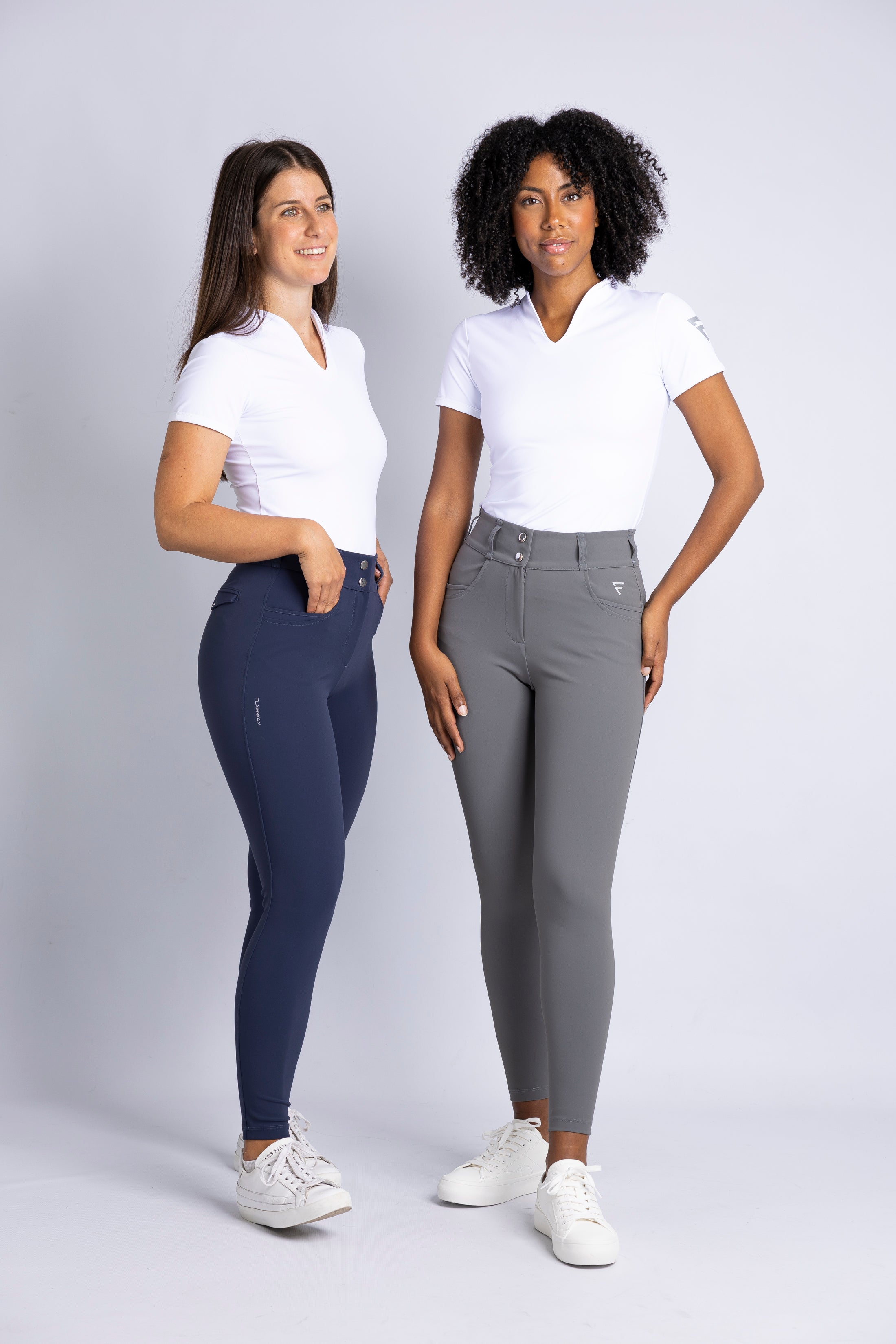 Two ladies wearing our modern collarless Calusa T-shirt (white) and our Raven stretch high-waisted pants (navy, grey) showcasing our innovative fabrics