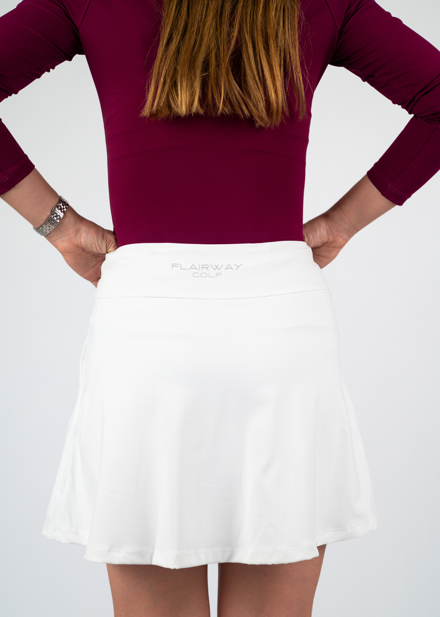 Person wearing a maroon top and white skirt with 'Flaviana' branding on a plain background