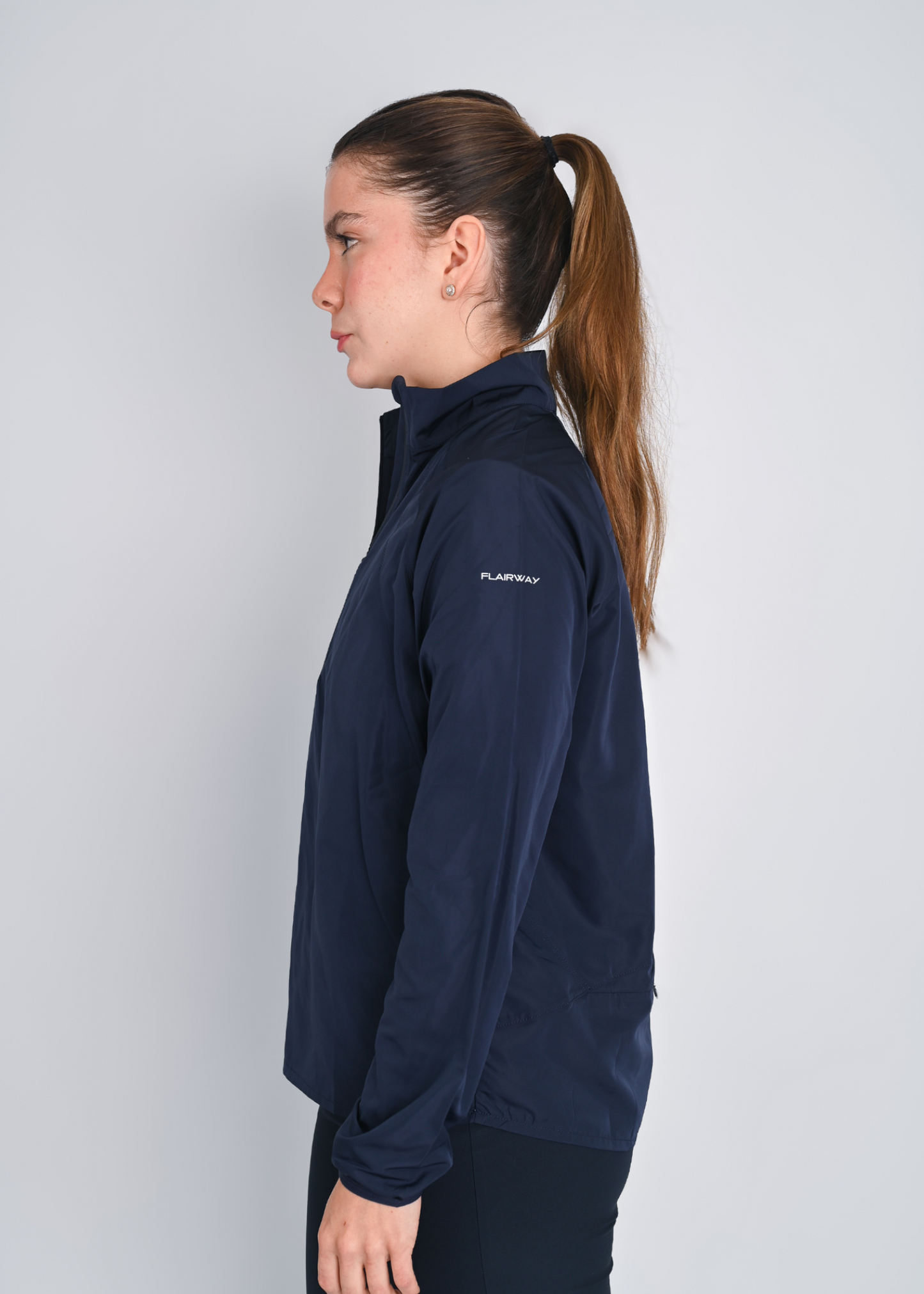 Woman wearing a navy blue jacket with a brand logo on a light gray background