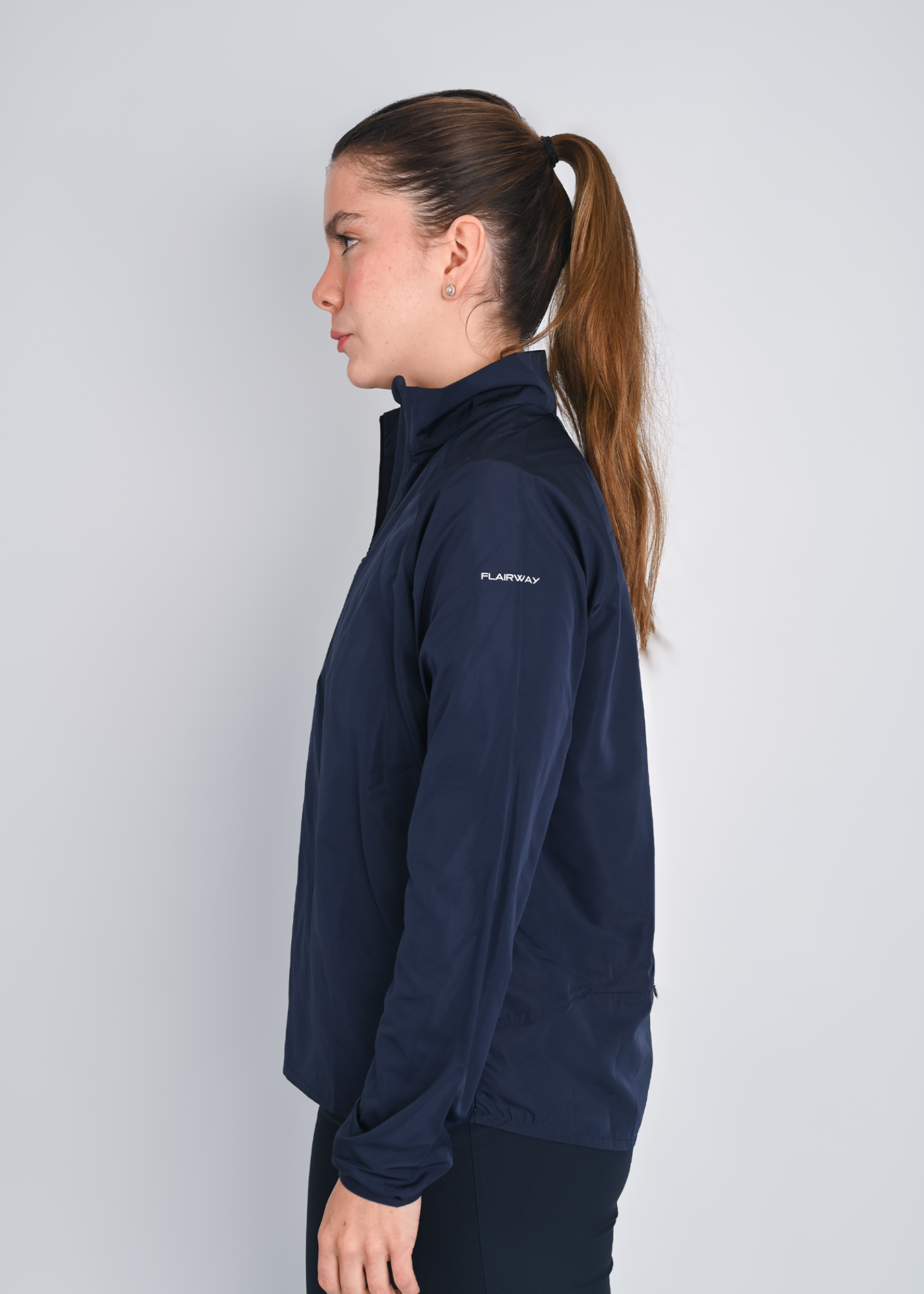Woman wearing a navy blue jacket with a brand logo on a light gray background